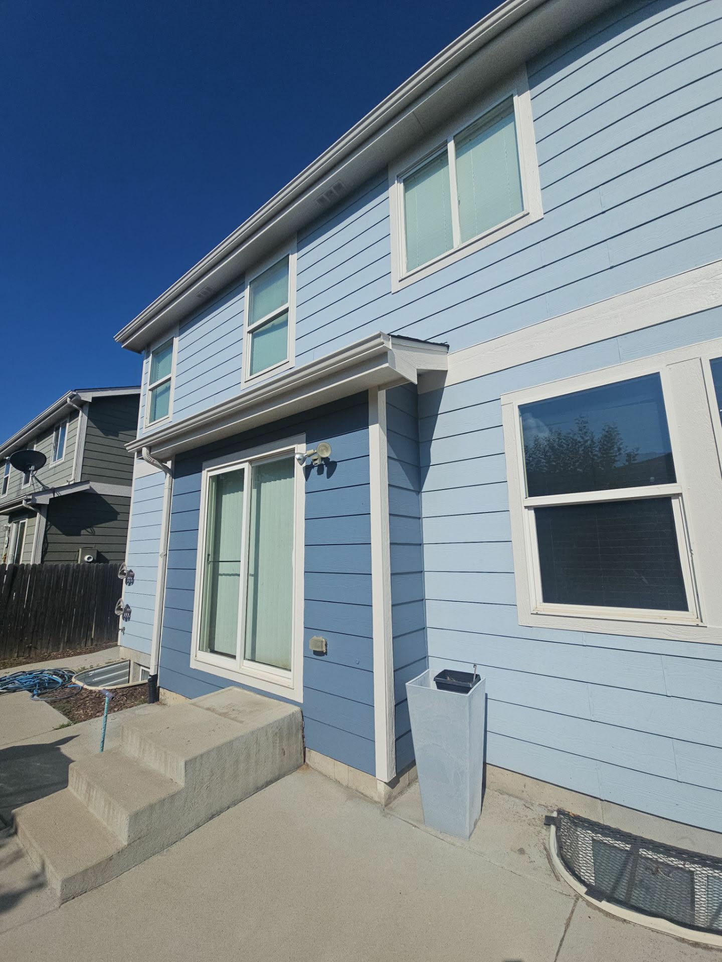 Light blue home side entry with white window trim and painted concrete steps