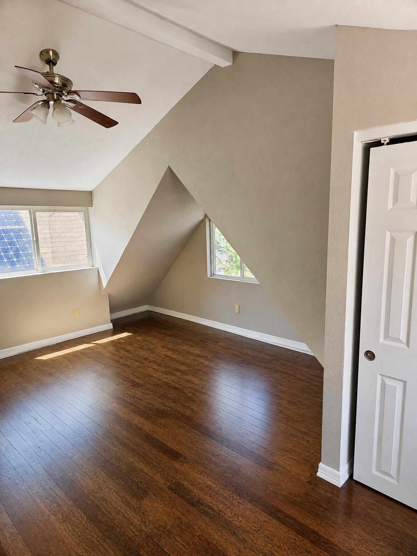 Bedroom painted warm greige with white trim and vaulted ceiling detail