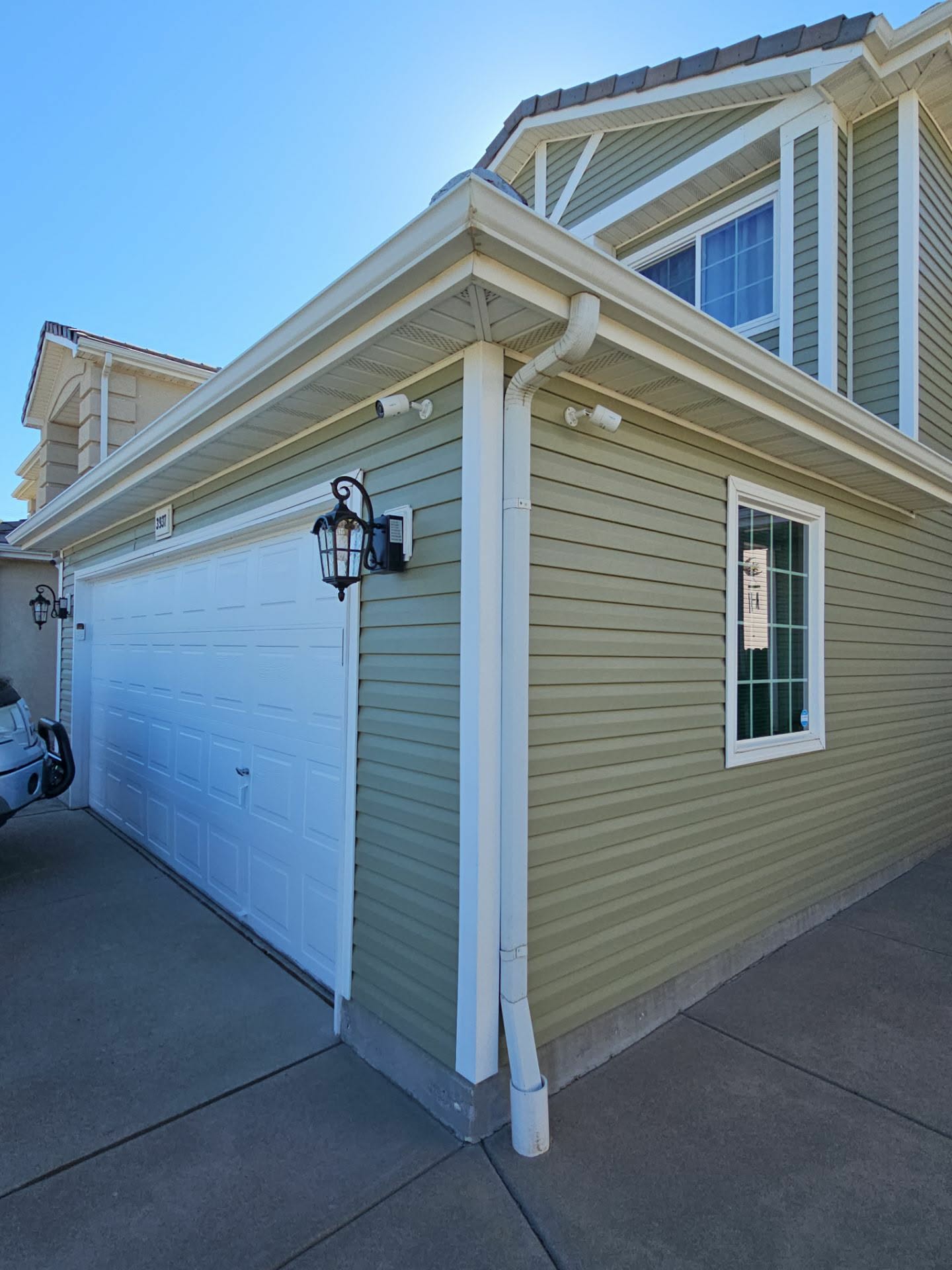 Sage green home exterior with bright white trim, gutters, and downspouts