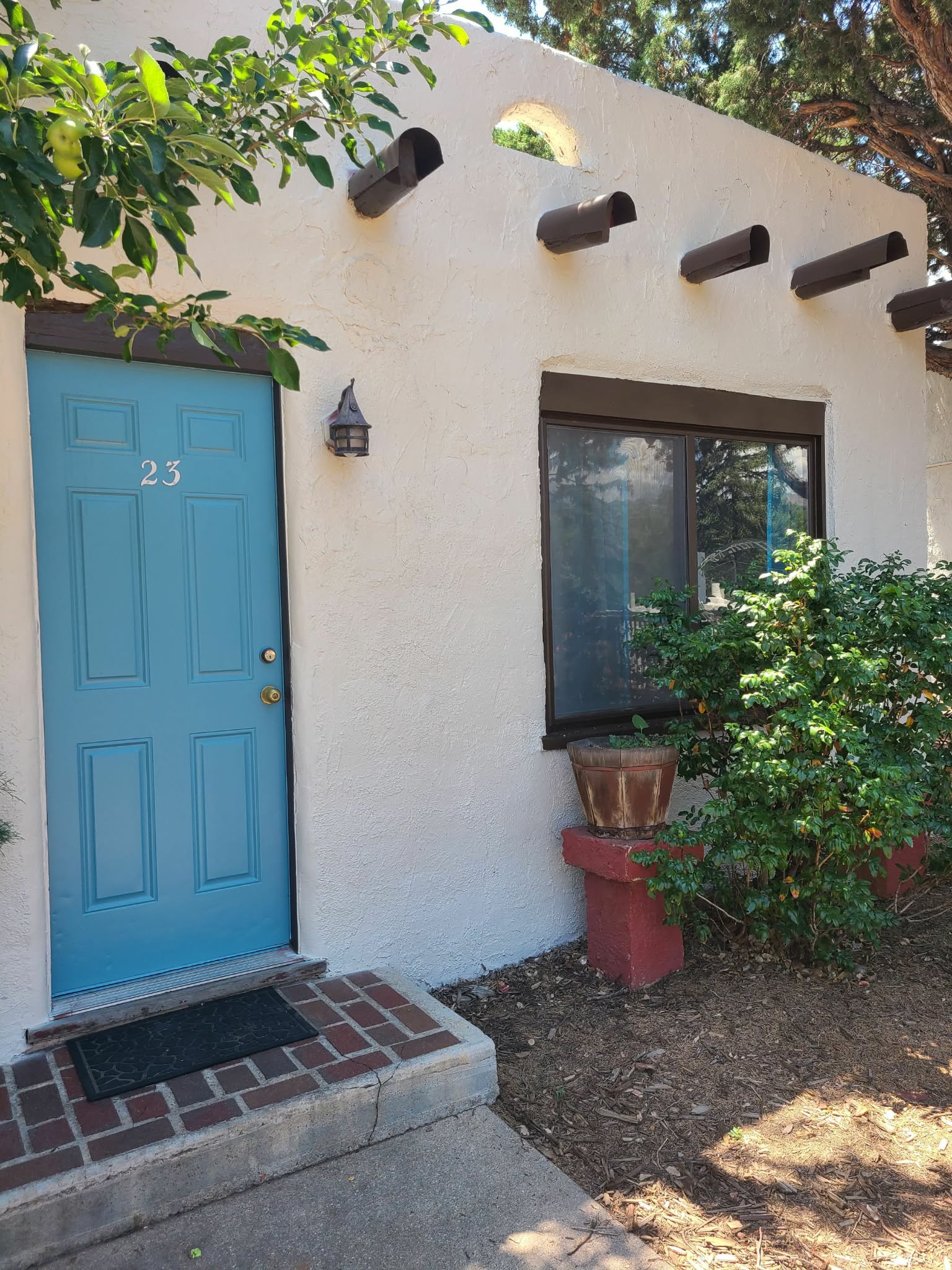 Adobe storefront entry with a repainted teal door and cream stucco walls