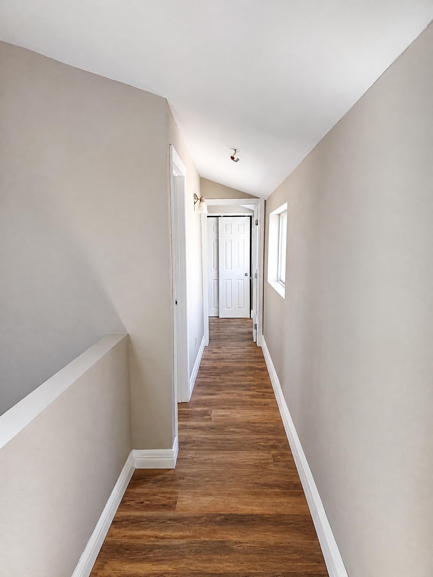 Upstairs hallway painted greige with bright white baseboards and doors