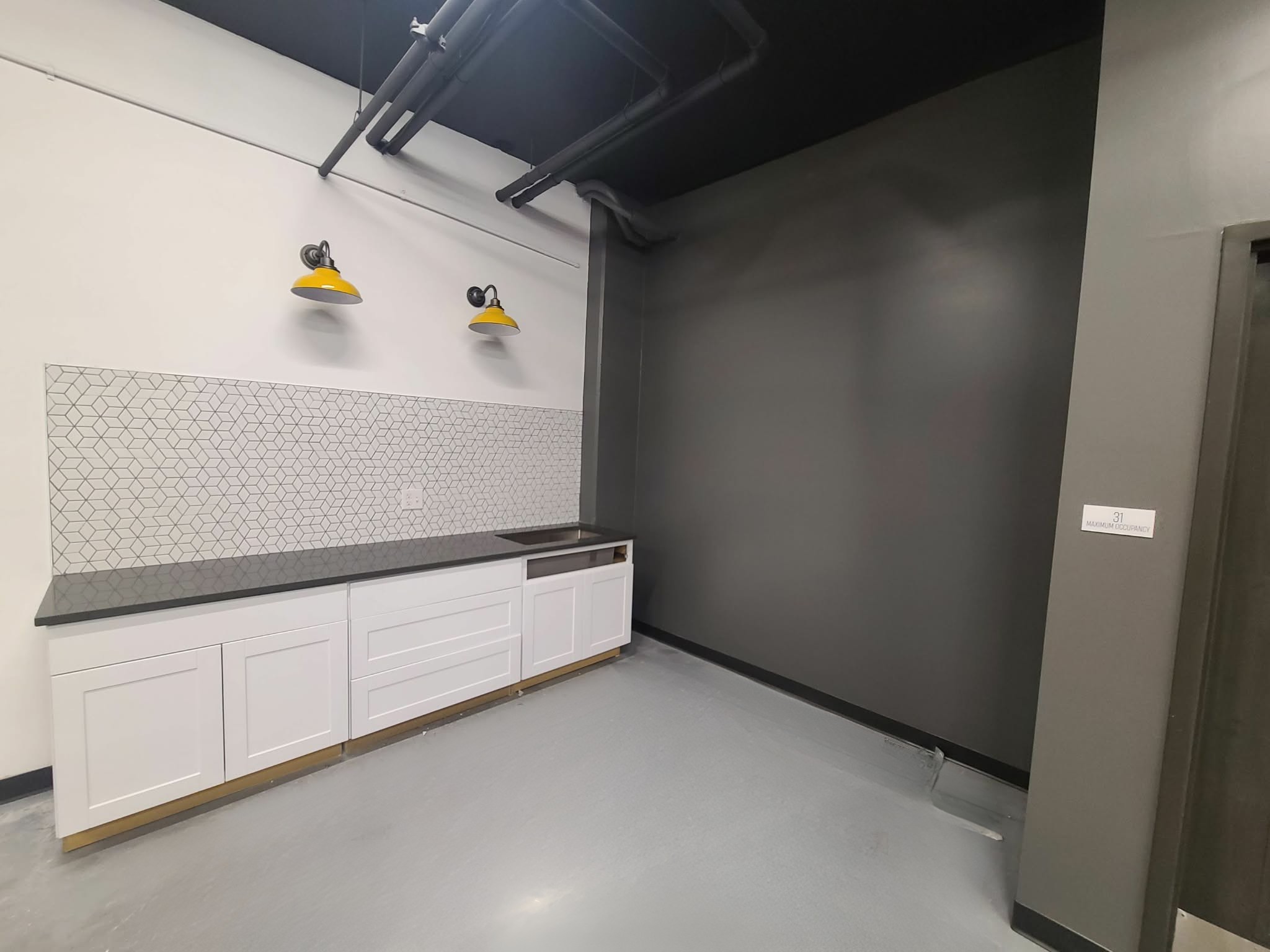 Commercial break area with white cabinetry and a charcoal accent wall