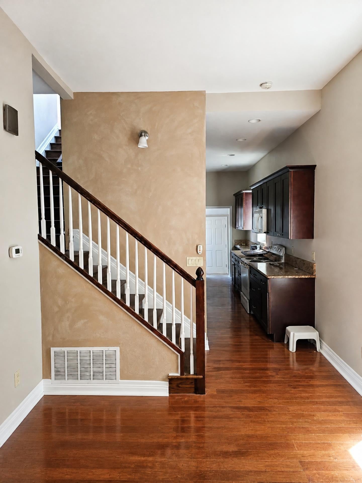 Entry staircase and kitchen with freshly painted walls and white railings