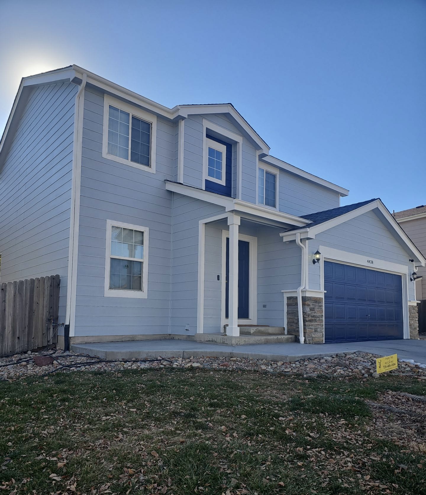 Light blue two-story home exterior with crisp white trim and navy garage door