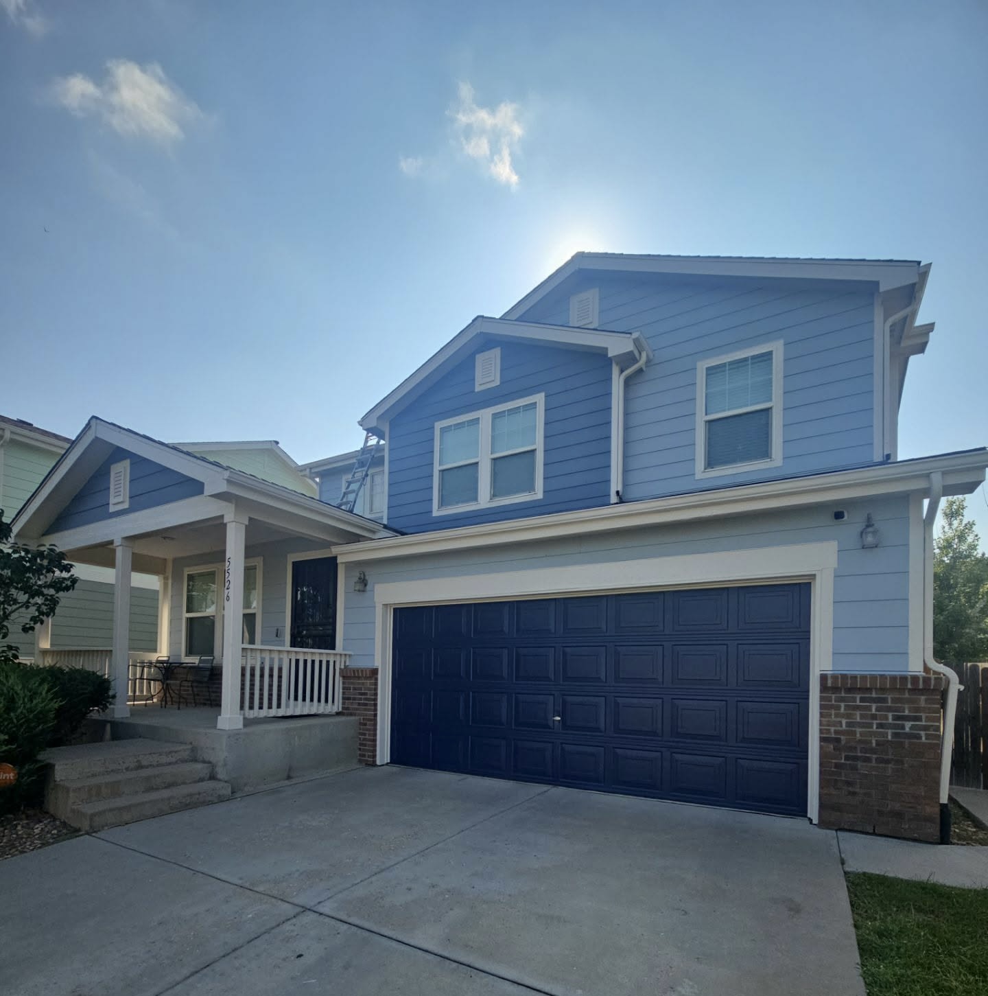Blue two-story home with fresh white trim and a repainted navy garage door