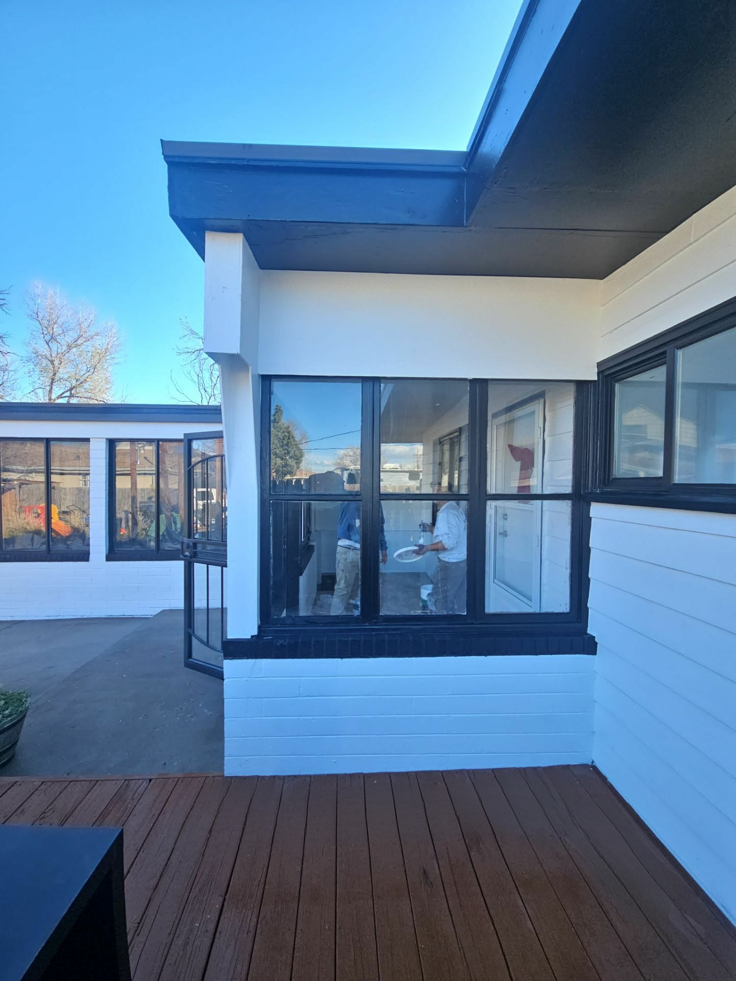 Modern home exterior finished in white with deep navy fascia beside a refinished deck