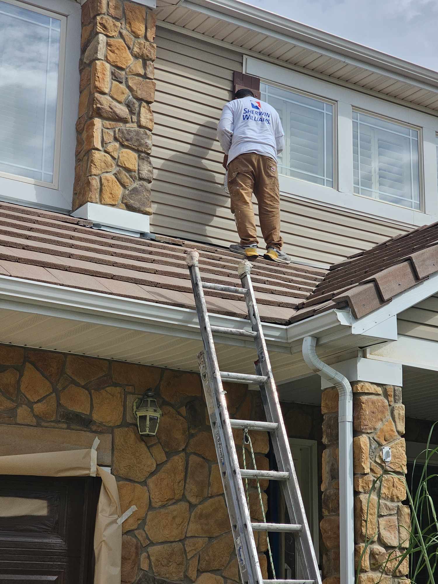 Hi-Def Restorations painter on a roofline cutting in siding and trim