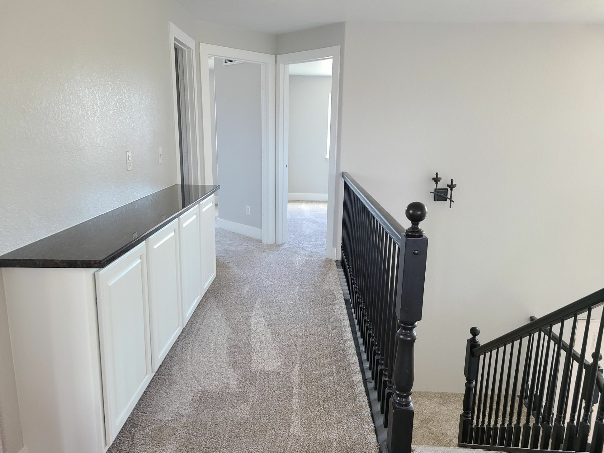 Upstairs hallway painted soft white with crisp trim, black railings, and built-in cabinetry