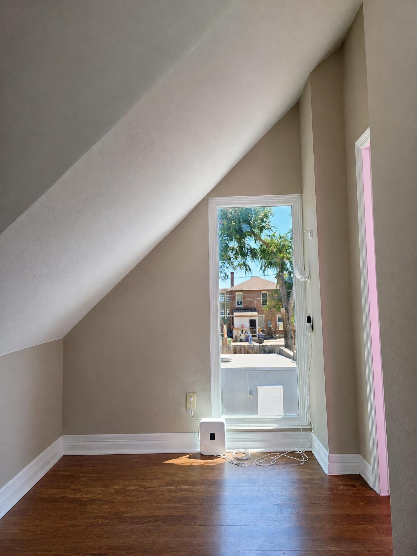 Attic bedroom with newly painted sloped ceilings and white window trim