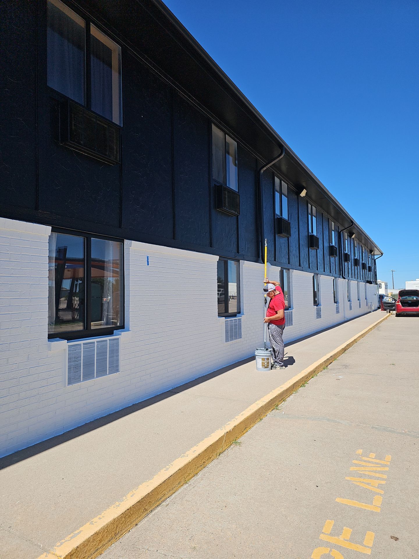 Hi-Def Restorations crew repainting a long two-story commercial building white and black