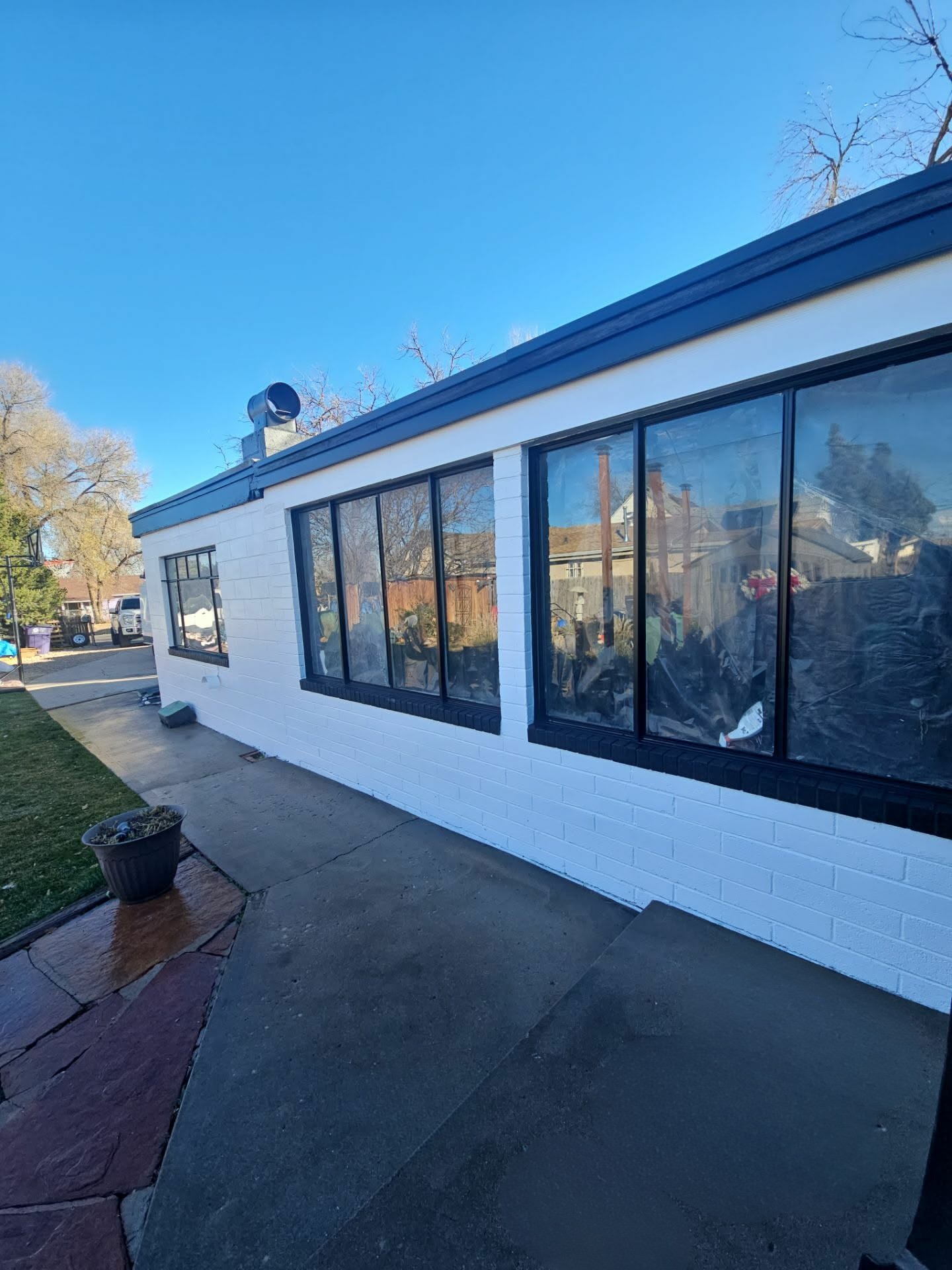 Long white exterior wall with black window frames after a full repaint